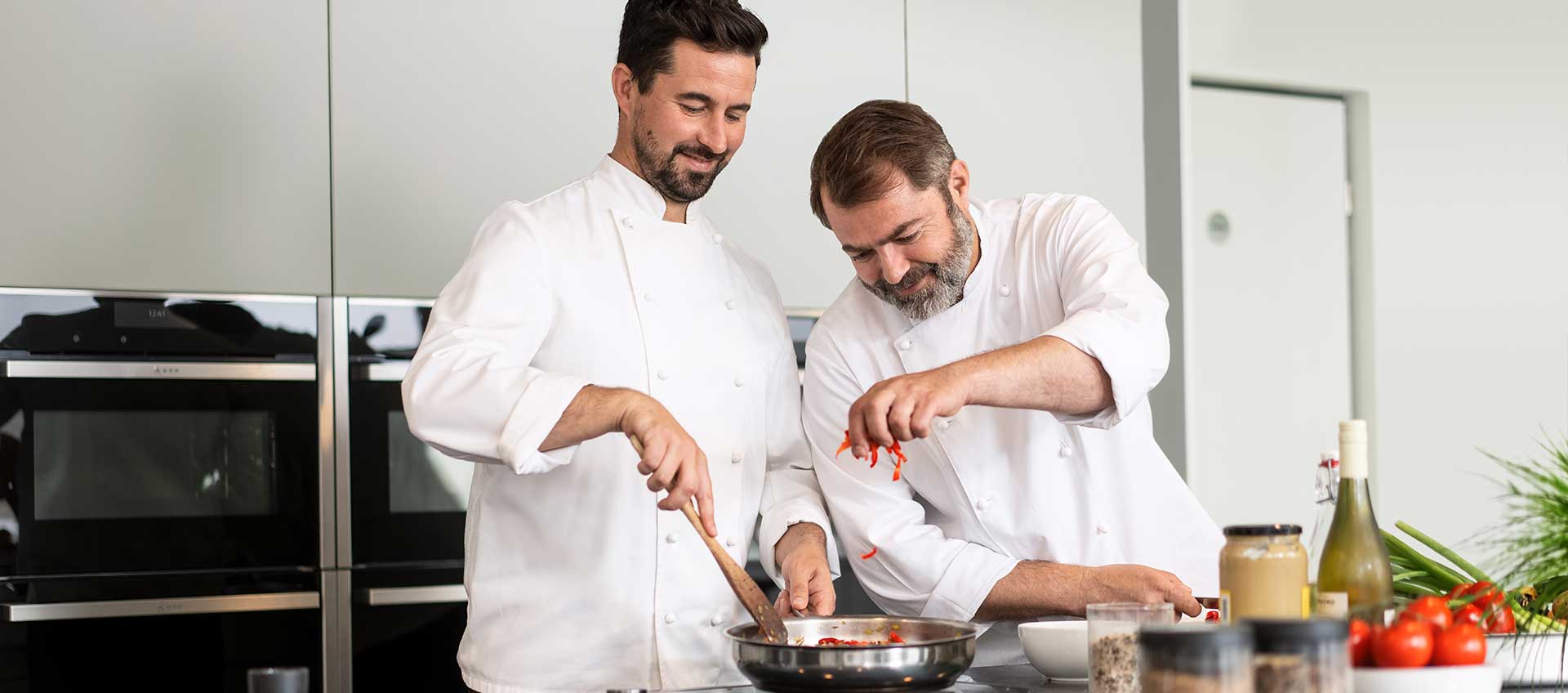 Zwei Köche bereiten in einer Küche ein Pfannengericht zu